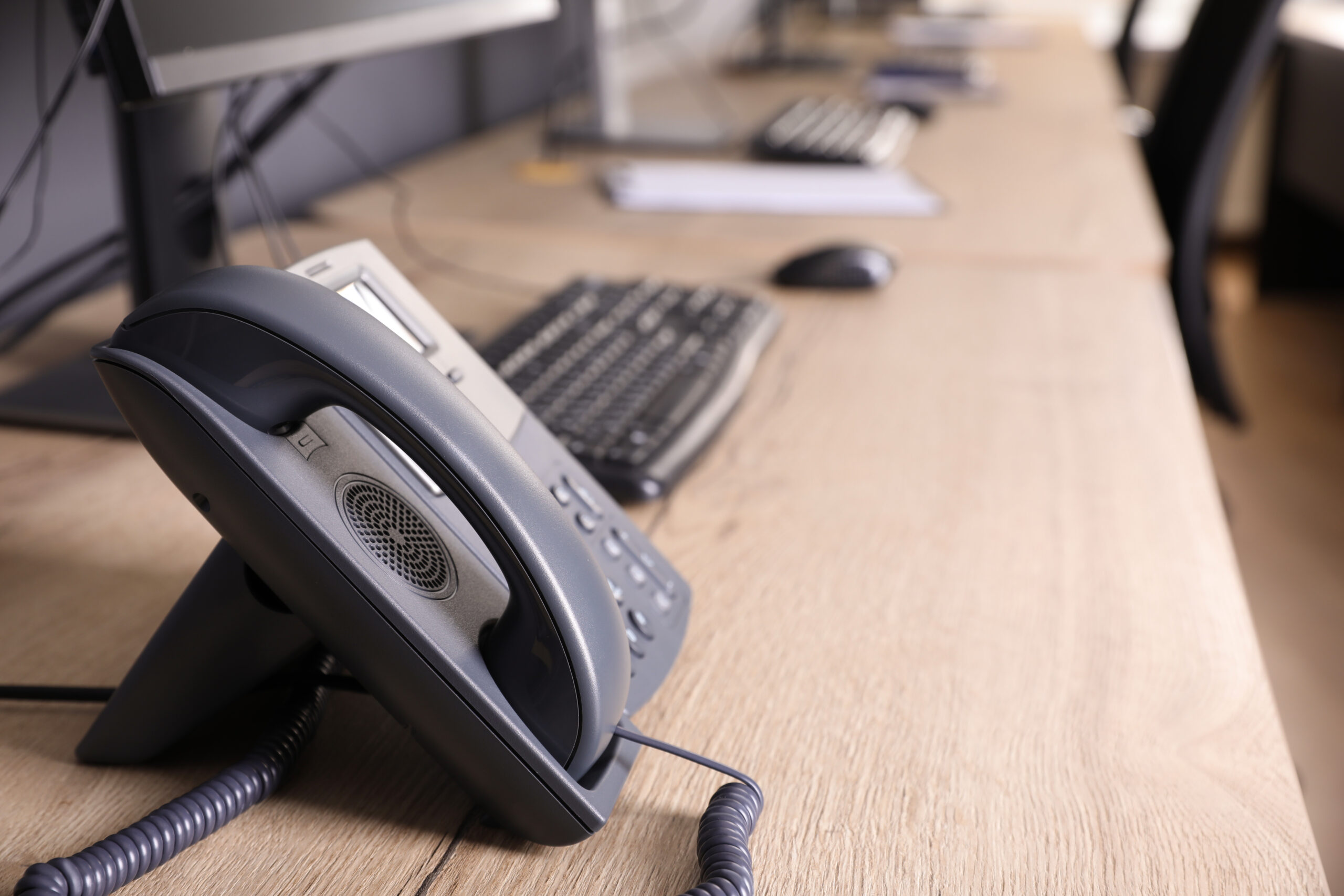 Stationary phone near modern computer on wooden desk in office. Investment Management
